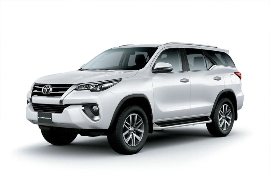 White Toyota Fortuner SUV photographed from a three-quarter front-right angle in a studio setting, showing its grille and headlights.