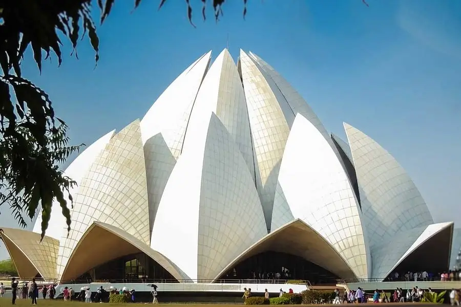 Lotus Temple in Delhi with petal-shaped white concrete structures and visitors walking around the plaza outside the building