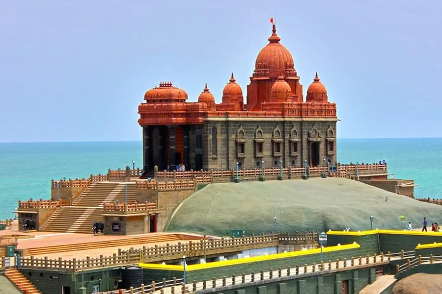 Hindu temple with red domes on a rocky platform extending into the sea, connected by terraces and steps